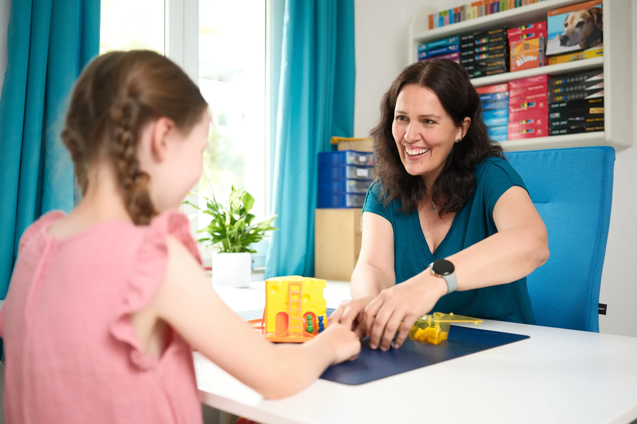 Logopädin übt spielerisch mit einem Mädchen am Tisch
